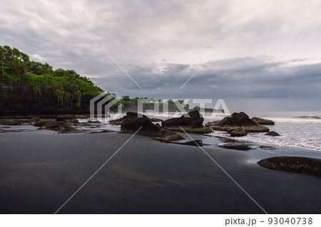 Black sand beach with ocean and waves in Balian, Bali. Beach with stones and cloudy sky Black sand beach with ocean and waves in Balian, Bali. Beach with stones and cloudy sky 93040738