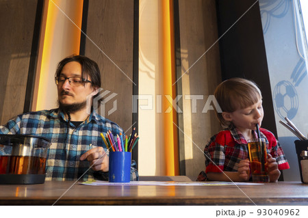 Portrait of child with his father drawing with pencils in cafe 93040962