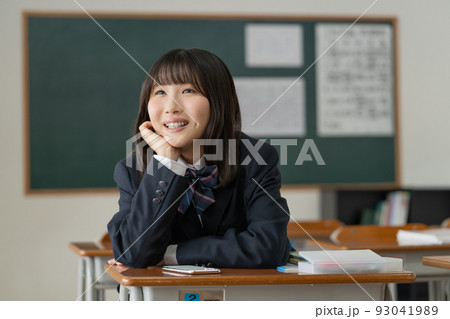 学校の教室で休み時間に頬杖をついて友達と会話する女子高生 93041989