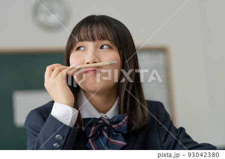 学校の教室でボールペンを鼻と口の間に挟んでふざける女子高生 93042380