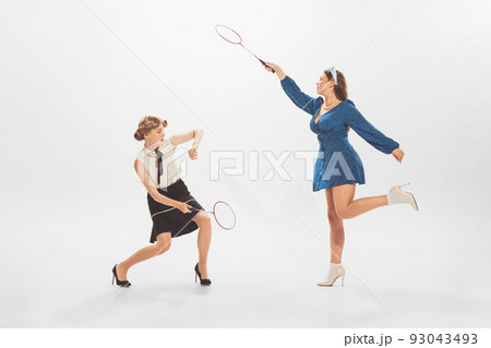 Portrait of young beautiful, stylish women playing badminton, posing isolated over white studio background 93043493