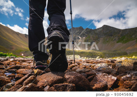 Close-up of women's hiking boots walking along a stone path in the mountains towards the lake 93045692