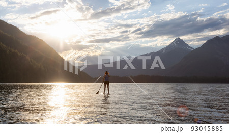 Adventurous Woman Paddle Boarding in a Lake around Canadian Mountain Landscape Adventurous Woman Paddle Boarding in a Lake around Canadian Mountain Landscape 93045885