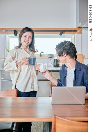 ダイニングキッチンでくつろぐ若いカップル 93046343