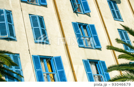 Closed and open blue shutters on windows at building 93046679