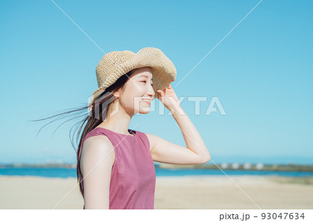 海辺で遊ぶ麦わら帽子をかぶった女性 93047634