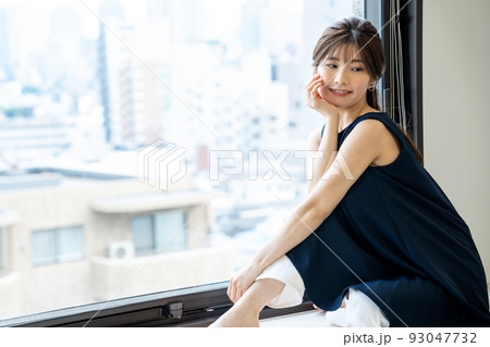 窓際に座って寛ぐ若い女性 93047732