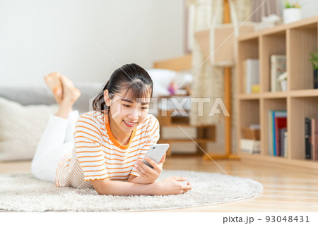 部屋でスマホを操作する若い女性。 部屋でスマホを操作する若い女性。 93048431