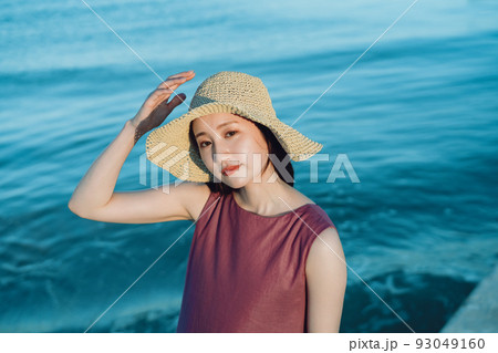 海辺で遊ぶ麦わら帽子の若い女性 93049160