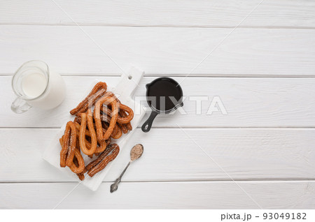 Homemade churros with chocolate on a white wooden background. Homemade churros with chocolate on a white wooden background. 93049182