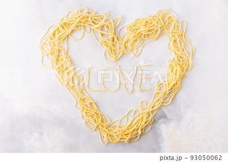 Decorative heart shaped pasta still life formed of pasta topped with tomatoes, basil 93050062
