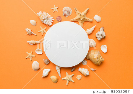 Summer time concept with blank greeting card and blank white paper on colored background. Seashells from ocean shore in the shape of frame separated with space for text top view Summer time concept with blank greeting card and blank white paper on colored background. Seashells from ocean shore in the shape of frame separated with space for text top view 93052097