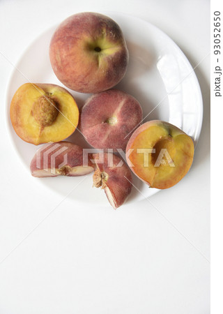 Nectarine and peaches cut into slices on a white plate. 93052650
