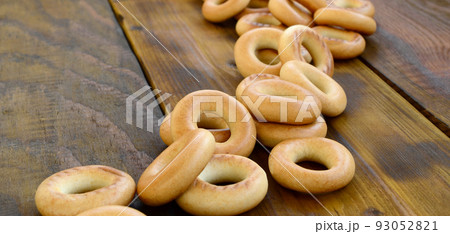 A lot of fresh yellow bagels lie on the surface of the old dark wood. A popular kind of flour products. One of the traditional Russian treats for tea A lot of fresh yellow bagels lie on the surface of the old dark wood. A popular kind of flour products. One of the traditional Russian treats for tea 93052821