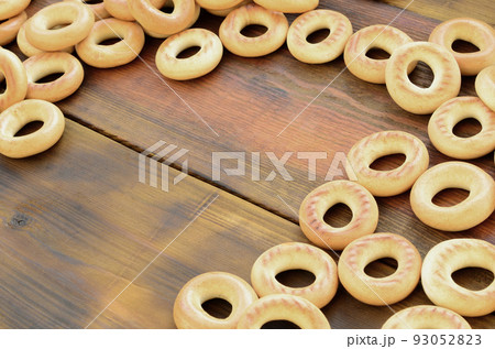 A lot of fresh yellow bagels lie on the surface of the old dark wood. A popular kind of flour products. One of the traditional Russian treats for tea A lot of fresh yellow bagels lie on the surface of the old dark wood. A popular kind of flour products. One of the traditional Russian treats for tea 93052823