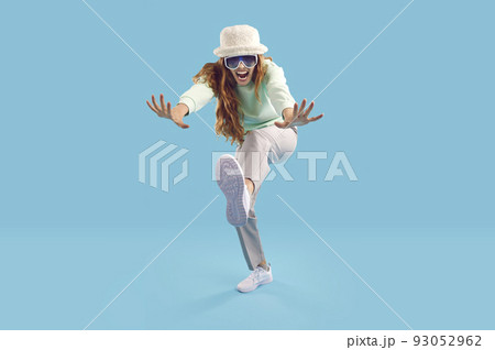Cheerful crazy and strange young woman having fun on light blue background in studio. Cheerful crazy and strange young woman having fun on light blue background in studio. 93052962