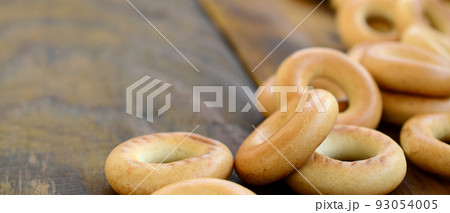 A lot of fresh yellow bagels lie on the surface of the old dark wood. A popular kind of flour products. One of the traditional Russian treats for tea A lot of fresh yellow bagels lie on the surface of the old dark wood. A popular kind of flour products. One of the traditional Russian treats for tea 93054005