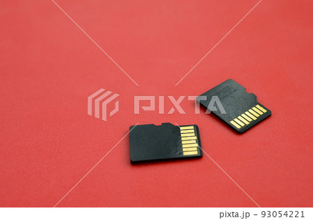 Two small micro SD memory cards lie on a red background. A small and compact data and information store Two small micro SD memory cards lie on a red background. A small and compact data and information store 93054221