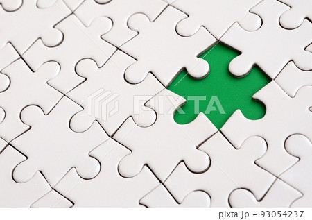 Close-up texture of a white jigsaw puzzle in assembled state with missing elements forming a green pad for text. Copy space Close-up texture of a white jigsaw puzzle in assembled state with missing elements forming a green pad for text. Copy space 93054237