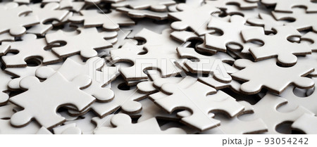 Close-up of a pile of uncompleted elements of a white puzzle. A huge number of rectangular pieces from one large white mosaic Close-up of a pile of uncompleted elements of a white puzzle. A huge number of rectangular pieces from one large white mosaic 93054242