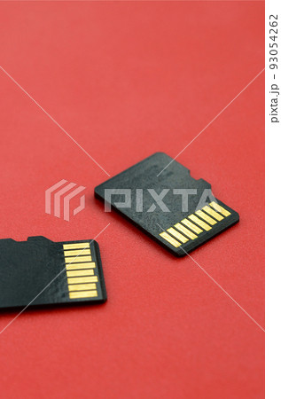 Two small micro SD memory cards lie on a red background. A small and compact data and information store Two small micro SD memory cards lie on a red background. A small and compact data and information store 93054262