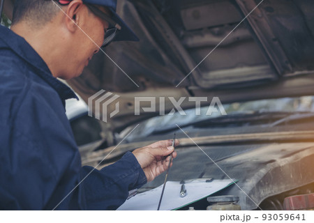 Car Mechanic man hand checking dipstick engine oil car mechanical on site service. Close up hand man check engine oil level Locate dipstick, wipe clean, check dipstick level before fill up engine oil 93059641