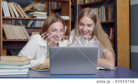 4K. The girls study together in the library. Students prepare for exams, write notes. 93059736
