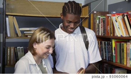 4K. An African-American man and a girl communicate in the library 4K. An African-American man and a girl communicate in the library 93060064
