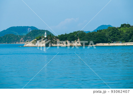 青い海を見下ろして立つ白い灯台 93062407