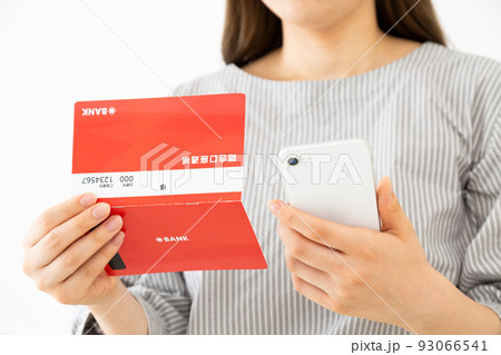 通帳とスマホを持つ若い女性 93066541