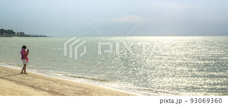 a woman takes picture on the sea beach with smartphone 93069360