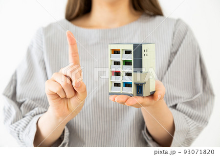 マンションの模型を持つ若い女性 93071820