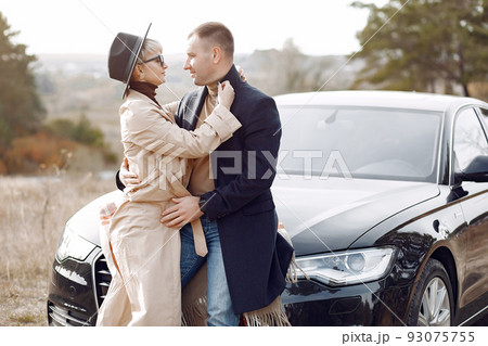Couple in a field. Girl in a brown coat. Man with his wife near the car Couple in a field. Girl in a brown coat. Man with his wife near the car 93075755