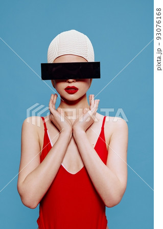 Be hidden. Prohibited content. A slender girl in a red swimsuit swimming cap holds her hands showing a sign In on a blue background 93076168