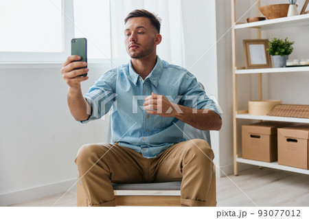 Narcissistic selfish self-confident handsome young man doing selfie video call with girlfriend holding phone admiring himself at home. Copy space for ad. Mobile App concept. Fashion offer Banner 93077012