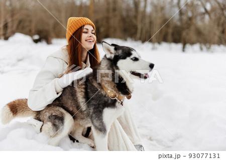cheerful woman outdoors in a field in winter walking with a dog winter holidays 93077131