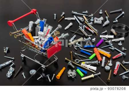 Different types of fasteners in a supermarket trolley. Place for text or logo. Concept: fastener store. Background of dark wood and a lot of fasteners. Different types of fasteners in a supermarket trolley. Place for text or logo. Concept: fastener store. Background of dark wood and a lot of fasteners. 93078208