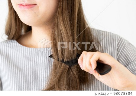 ロングヘアの髪の毛をクシでとかす若い女性 93078304