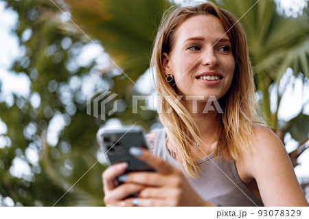 Young casual woman using her smartphone in the city. Young casual woman using her smartphone in the city. 93078329