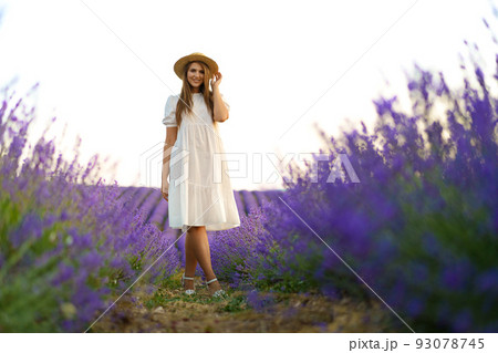 Young woman in a white dress walking in a lavender field Young woman in a white dress walking in a lavender field 93078745