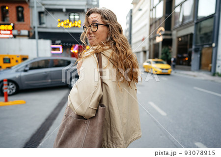 Young beautiful pretty woman walking along the street in modern city 93078915