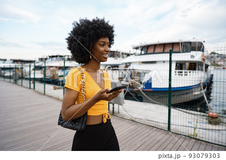 Portrait of a young african american woman smiling standing at the city. 93079303