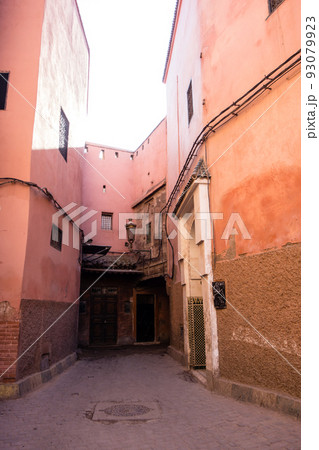 細道の脇に立つ赤茶色の建物　モロッコの街マラケッシュのメディナにて 93079923