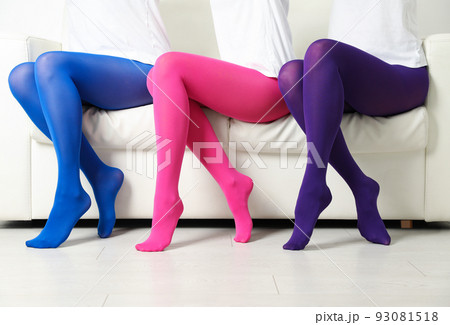 Women wearing colorful tights sitting on sofa indoors, closeup 93081518