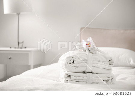 Clean folded bathrobes on bed in room, space for text 93081622