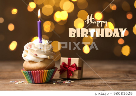 Delicious cupcake and gift box on wooden table against blurred lights. Happy Birthday Delicious cupcake and gift box on wooden table against blurred lights. Happy Birthday 93081629