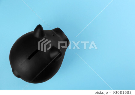 Black piggy bank on light blue background, top view. Space for text 93081682