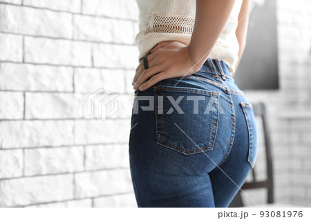Woman wearing jeans near brick wall indoors, closeup 93081976