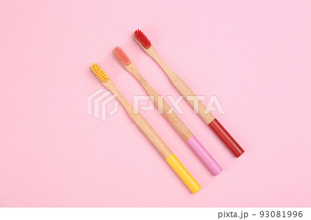 Toothbrushes made of bamboo on pink background, flat lay Toothbrushes made of bamboo on pink background, flat lay 93081996