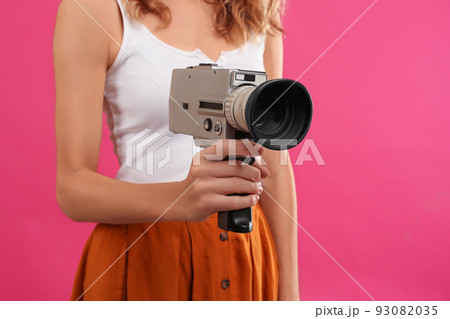 Woman with vintage video camera on crimson background, closeup Woman with vintage video camera on crimson background, closeup 93082035